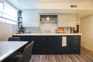 Kitchen featuring decorative backsplash, white cabinets, and dark hardwood / wood-style floors