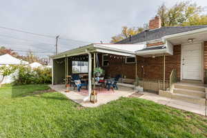 Rear view of property featuring a patio area and a lawn