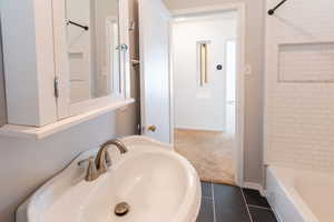 Bathroom featuring tiled shower / bath combo, tile patterned floors, and sink