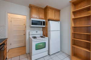 Kitchen featuring decorative backsplash, white appliances, and light tile patterned floors