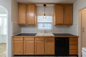 Kitchen featuring black dishwasher, sink, tasteful backsplash, and plenty of natural light