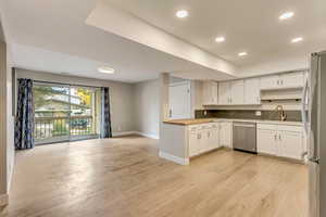 Kitchen featuring white cabinets, sink, light wood-type flooring, stainless steel appliances, and wooden counters