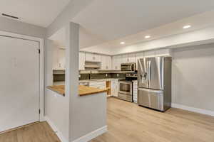 Kitchen featuring white cabinetry, light hardwood / wood-style floors, appliances with stainless steel finishes, and sink