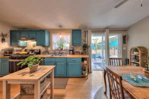 Kitchen featuring sink, a textured ceiling, hanging light fixtures, and light hardwood / wood-style floors