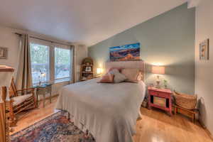 Bedroom with lofted ceiling and light wood-type flooring