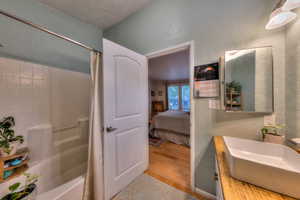 Bathroom with shower / tub combo with curtain, vanity, a textured ceiling, and hardwood / wood-style flooring