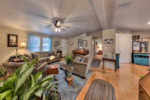 Living room featuring lofted ceiling with beams, a textured ceiling, light wood-type flooring, and ceiling fan