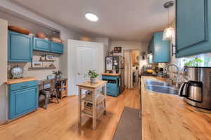 Kitchen featuring wood counters, blue cabinets, light hardwood / wood-style flooring, sink, and decorative light fixtures