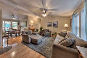 Living room with light hardwood / wood-style floors, lofted ceiling, a textured ceiling, and ceiling fan