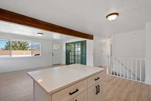 Kitchen featuring light hardwood / wood-style floors, a textured ceiling, a center island, and white cabinets