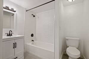 Full bathroom with vanity, toilet, a textured ceiling, and tiled shower / bath