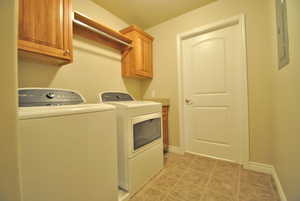 Washroom featuring electric panel, cabinets, and separate washer and dryer