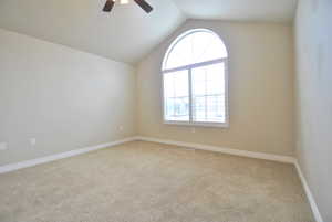 Unfurnished room with ceiling fan, vaulted ceiling, and light colored carpet