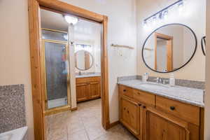 Bathroom featuring vanity, walk in shower, and tile patterned flooring