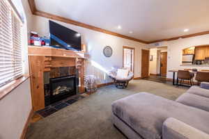 Carpeted living room featuring ornamental molding and a tile fireplace