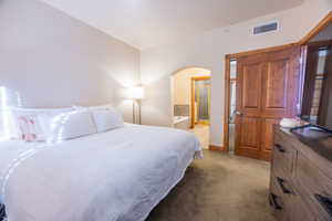 Bedroom featuring light carpet and connected bathroom