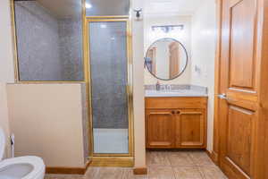 Bathroom with vanity, toilet, tile patterned floors, and an enclosed shower