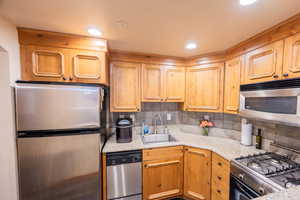 Kitchen featuring backsplash, appliances with stainless steel finishes, and sink