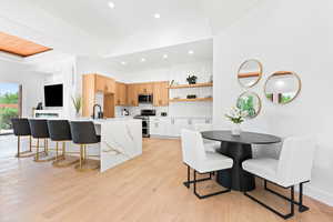 Kitchen featuring a tray ceiling, light hardwood / wood-style flooring, stainless steel appliances, and white cabinetry