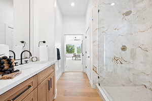 Bathroom featuring a tile shower, ceiling fan, hardwood / wood-style floors, and vanity