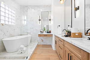 Bathroom featuring tile walls, vanity, hardwood / wood-style floors, and a tub to relax in