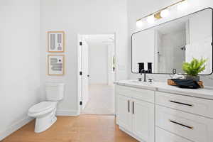 Bathroom with vanity, hardwood / wood-style flooring, toilet, and an enclosed shower