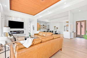 Living room with wood ceiling, light wood-type flooring, and a raised ceiling