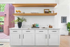 Bar with light stone countertops, a wealth of natural light, and white cabinets