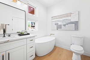 Bathroom featuring vanity, toilet, a tub to relax in, and wood-type flooring