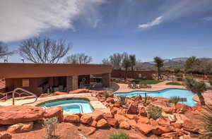 View of pool with a hot tub, a mountain view, and a patio area