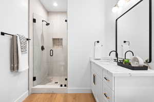 Bathroom with vanity, an enclosed shower, and wood-type flooring