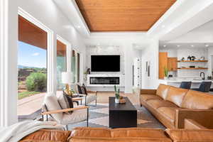 Living room featuring light hardwood / wood-style flooring, a raised ceiling, and wooden ceiling