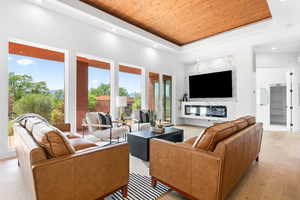 Living room with light hardwood / wood-style flooring, a tray ceiling, and wood ceiling