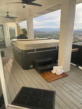 Deck featuring a hot tub, a mountain view, and ceiling fan