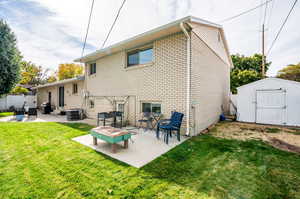 Rear view of house featuring a patio, a storage unit, central AC, and a yard