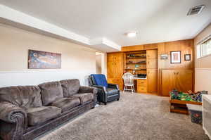 Living room with carpet floors, built in desk, and wooden walls