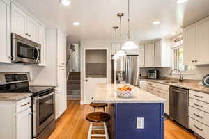 Kitchen with light hardwood / wood-style flooring, appliances with stainless steel finishes, sink, and a kitchen island