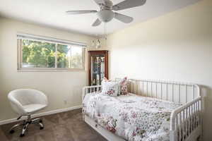 Bedroom featuring ceiling fan and dark colored carpet