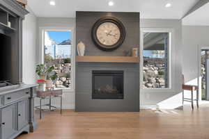 Living room featuring a wealth of natural light, a large fireplace, light hardwood / wood-style floors, and lofted ceiling