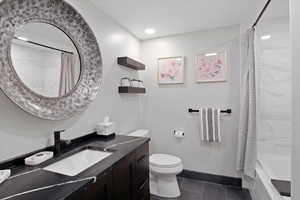 Full bathroom with toilet, shower / tub combo with curtain, vanity, and tile patterned floors