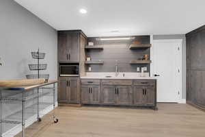 Kitchen featuring dark brown cabinets, light wood-type flooring, and sink