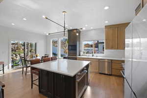 Kitchen featuring appliances with stainless steel finishes, a kitchen breakfast bar, hanging light fixtures, a kitchen island, and light wood-type flooring