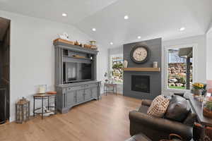 Living room with light hardwood / wood-style floors and lofted ceiling