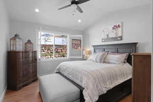 Bedroom with ceiling fan, light wood-type flooring, and vaulted ceiling