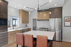 Kitchen with a kitchen island, light wood-type flooring, appliances with stainless steel finishes, and a breakfast bar