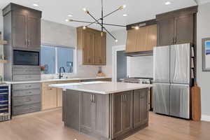 Kitchen with sink, pendant lighting, a center island, light hardwood / wood-style floors, and stainless steel refrigerator