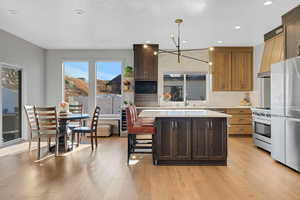 Kitchen featuring a center island, an inviting chandelier, light hardwood / wood-style flooring, pendant lighting, and appliances with stainless steel finishes