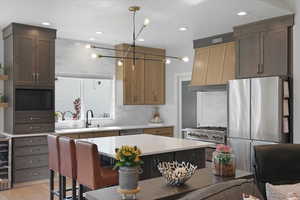 Kitchen featuring appliances with stainless steel finishes, a kitchen bar, backsplash, a kitchen island, and light wood-type flooring