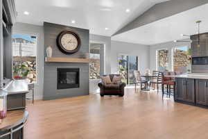 Living room with light wood-type flooring, a fireplace, a wealth of natural light, and vaulted ceiling