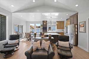 Living room featuring a chandelier, sink, light wood-type flooring, and vaulted ceiling